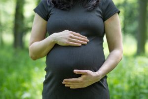 Eine werdende Mutter hält ihren Babybauch.